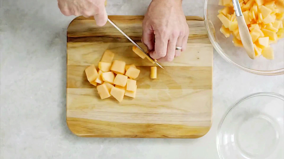Cantaloupe being cubed for melon cucumber salad