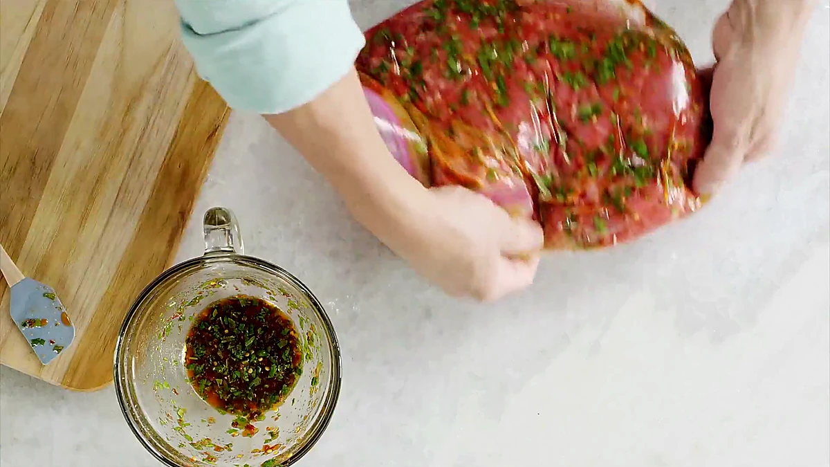 Flank steak coated in marinade inside a sealed bag