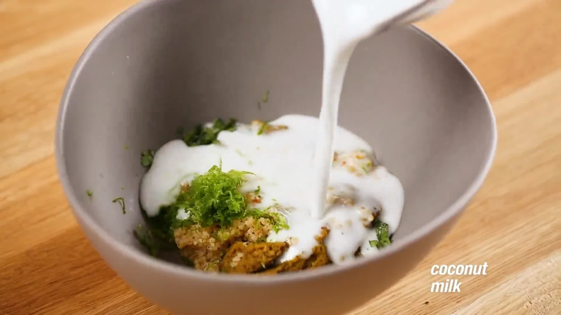 Coconut milk being poured into the curry paste bowl