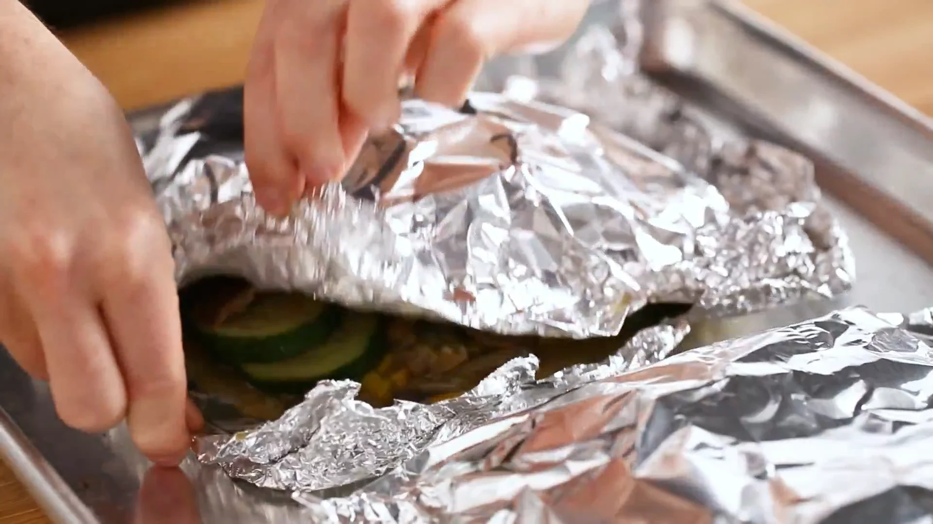 Foil packet opened to reveal cooked fish over zucchini and peppers