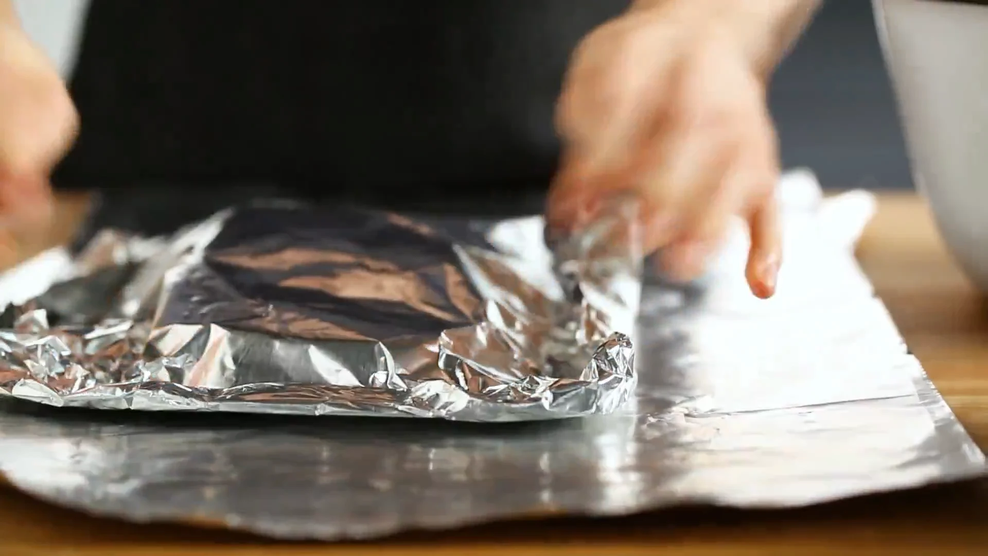 Sealed foil packets lined up on a sheet pan