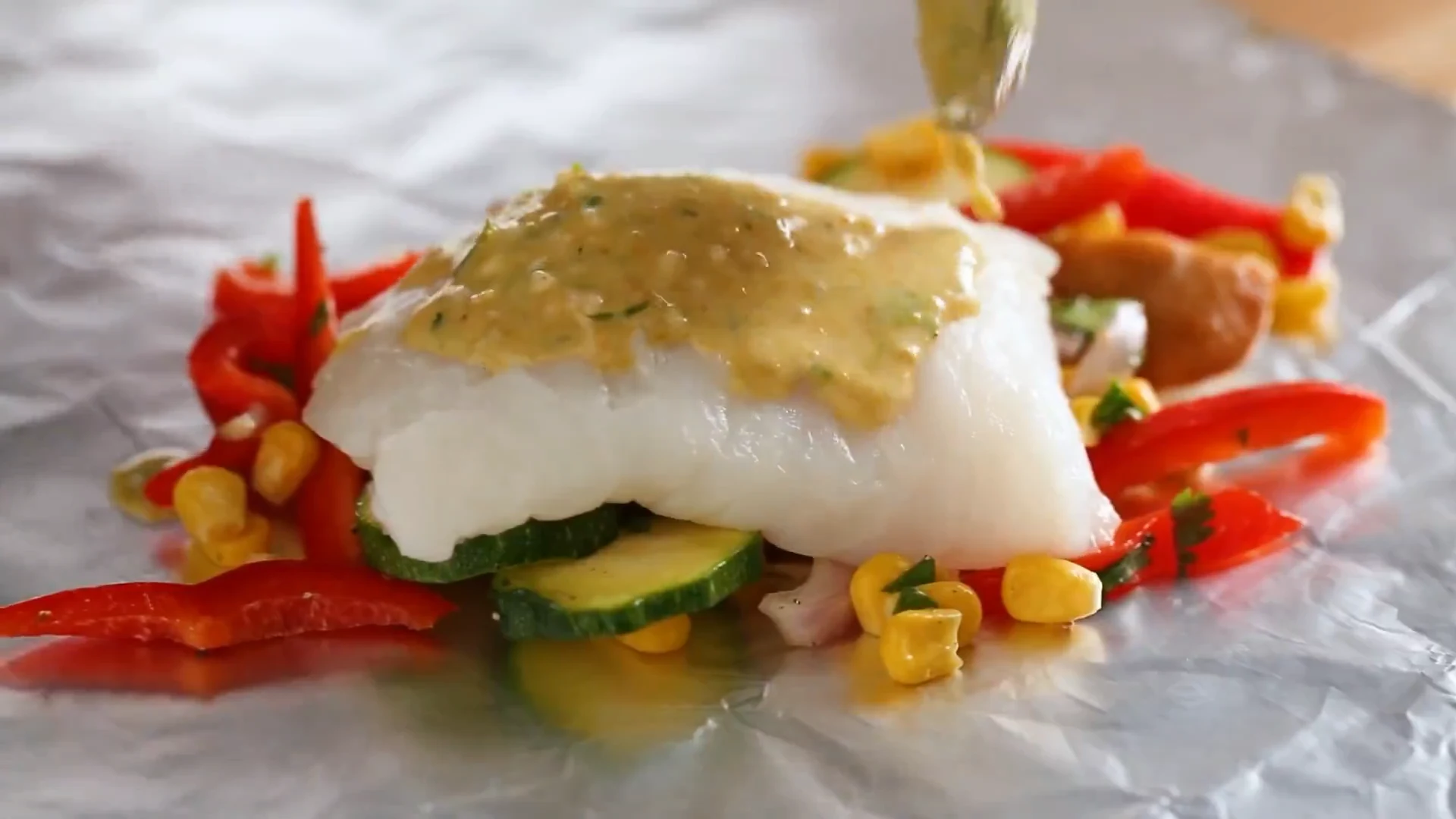 Coconut curry sauce spooned over a fish fillet on vegetables