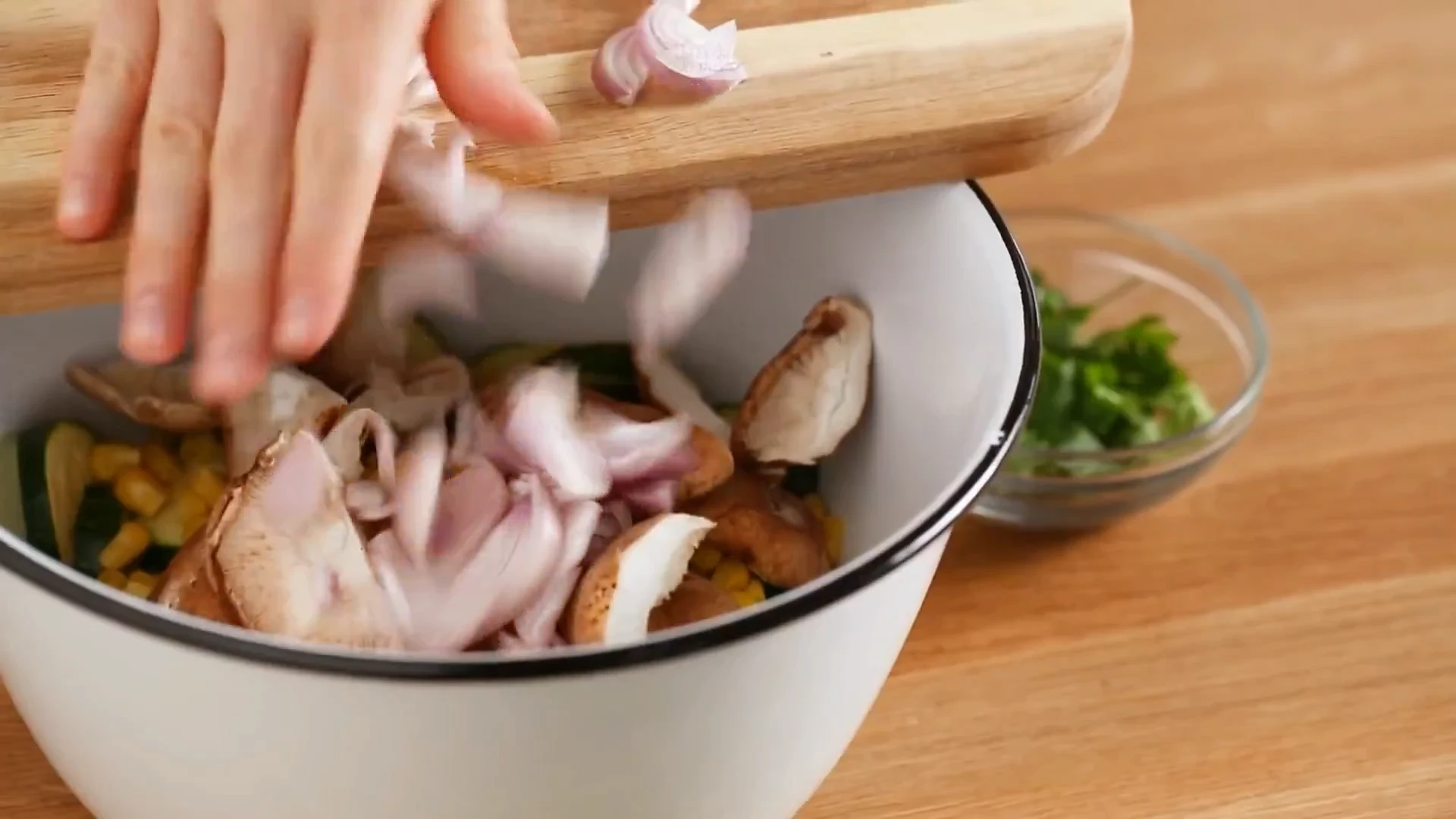 Sliced shallots added to the bowl of zucchini and mushrooms