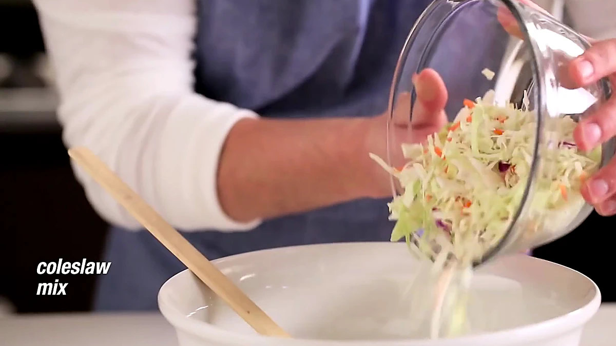 Coleslaw mix being poured into the creamy lime base