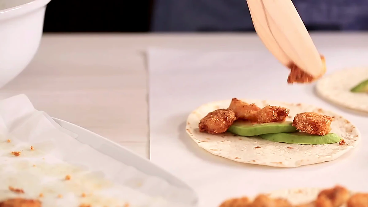 Crispy shrimp added over avocado on tortillas