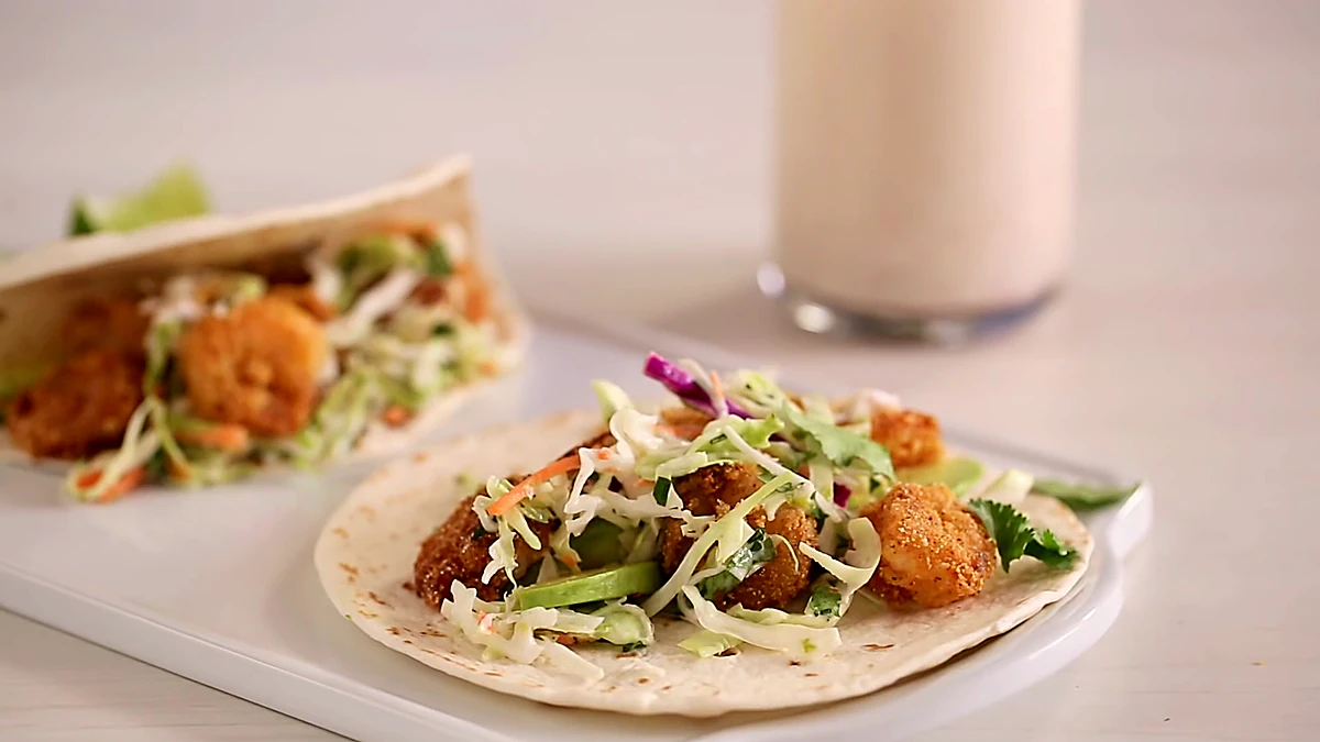 Finished crispy Baja shrimp tacos with slaw and avocado