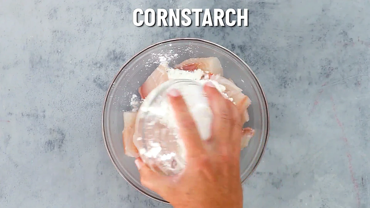 Cornstarch sprinkled over tilapia pieces