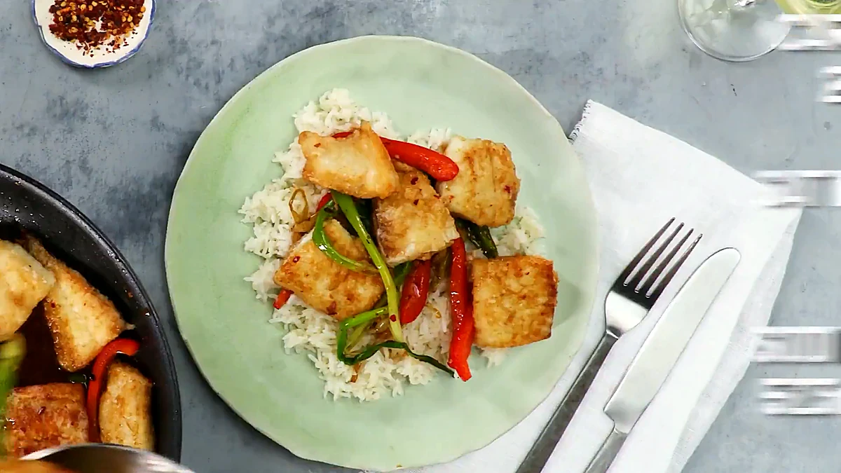Overhead plate of crispy fish with scallions and peppers