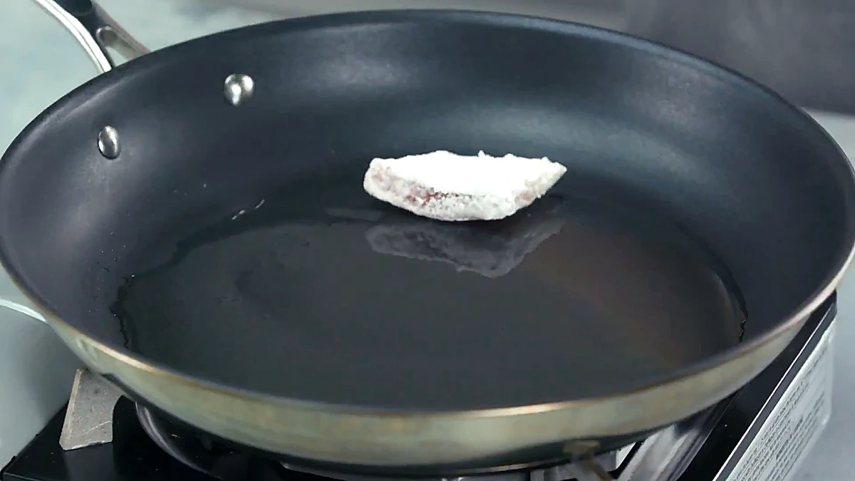 Coated tilapia added to the hot pan