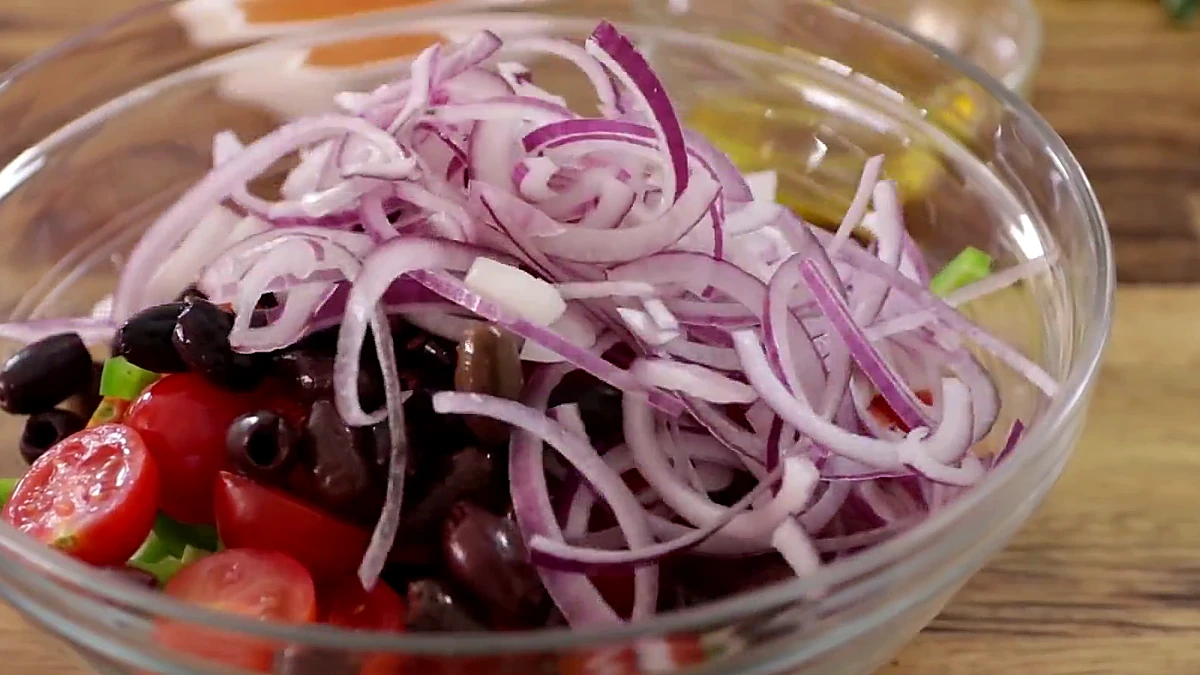 Drained red onion added to the Greek salad