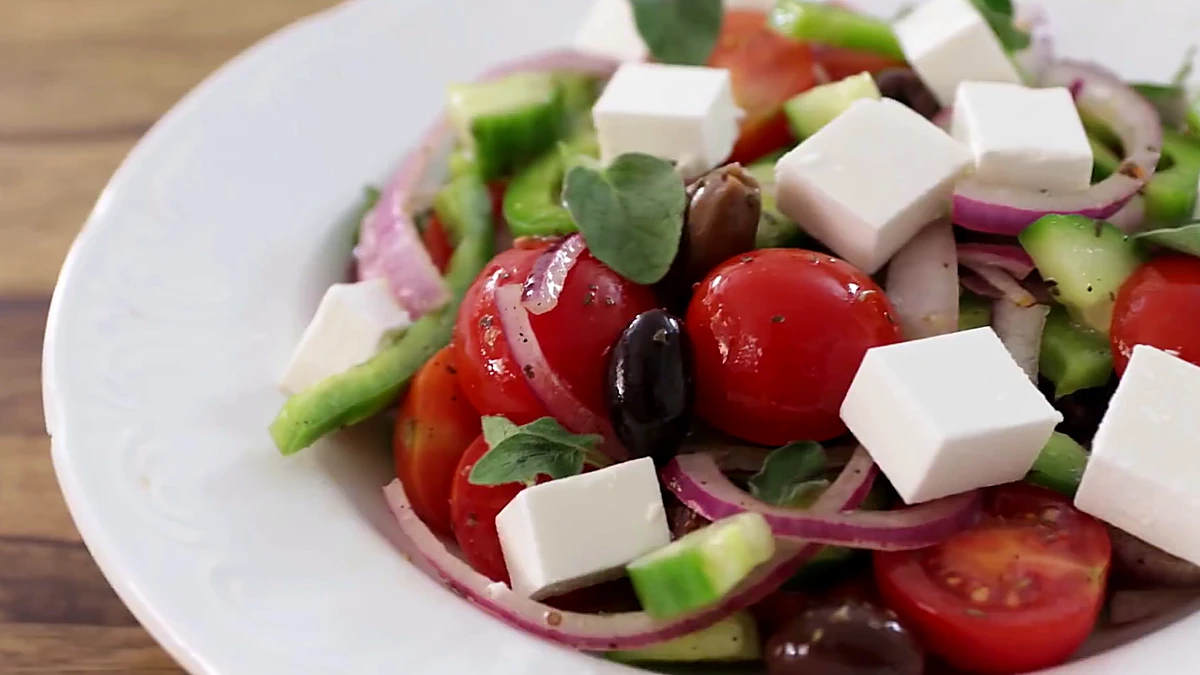 Finished Greek salad with fresh oregano leaves