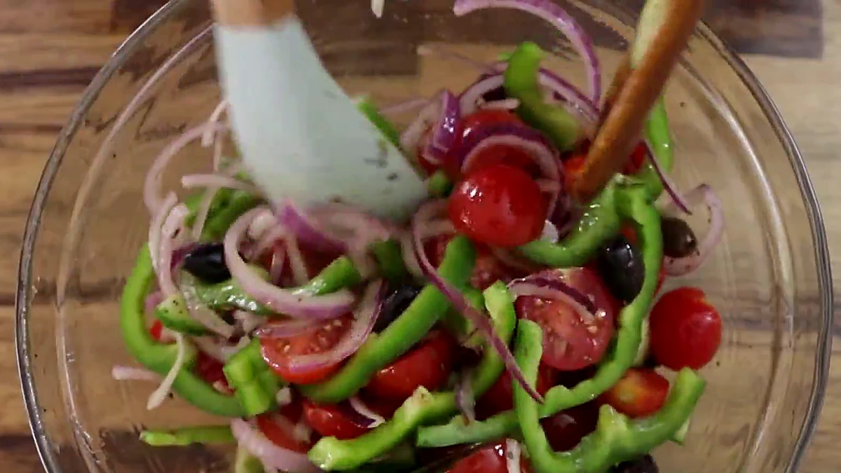 Greek salad tossed in a glass bowl