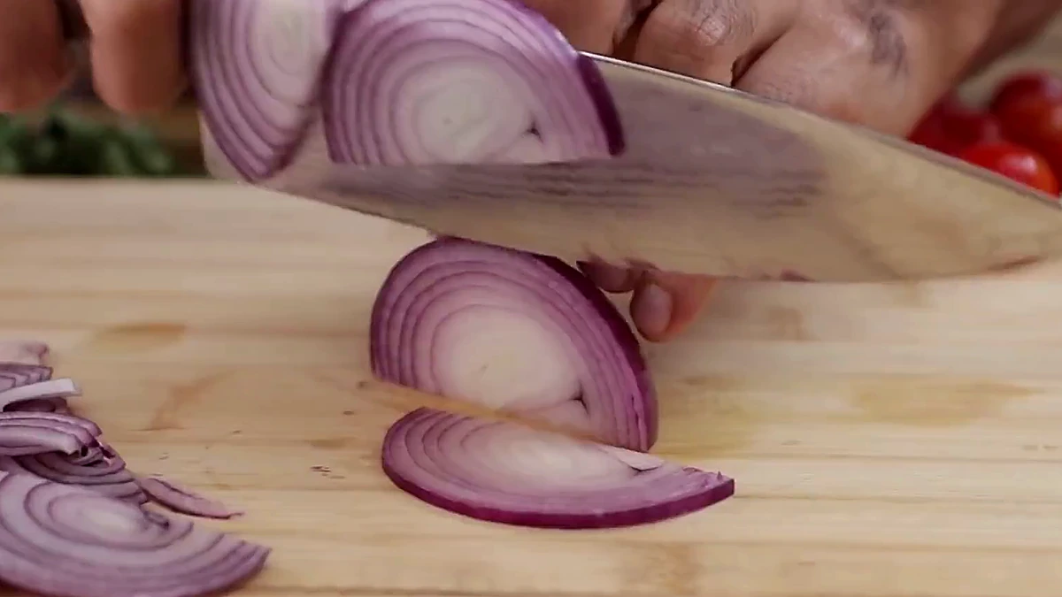 Red onion thinly sliced on a cutting board