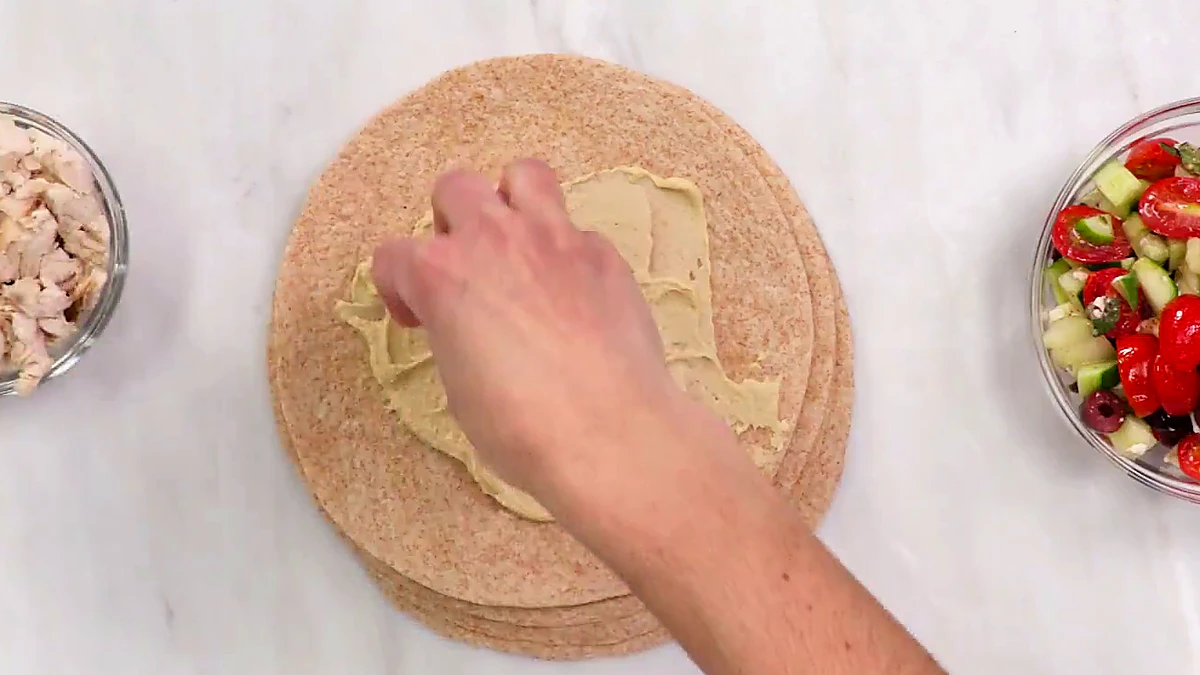 Rotisserie chicken added to hummus tortilla