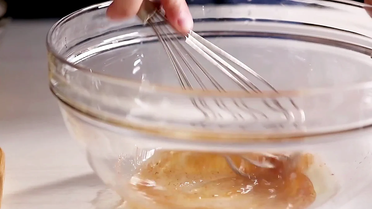 Honey lime dressing being whisked in a glass bowl