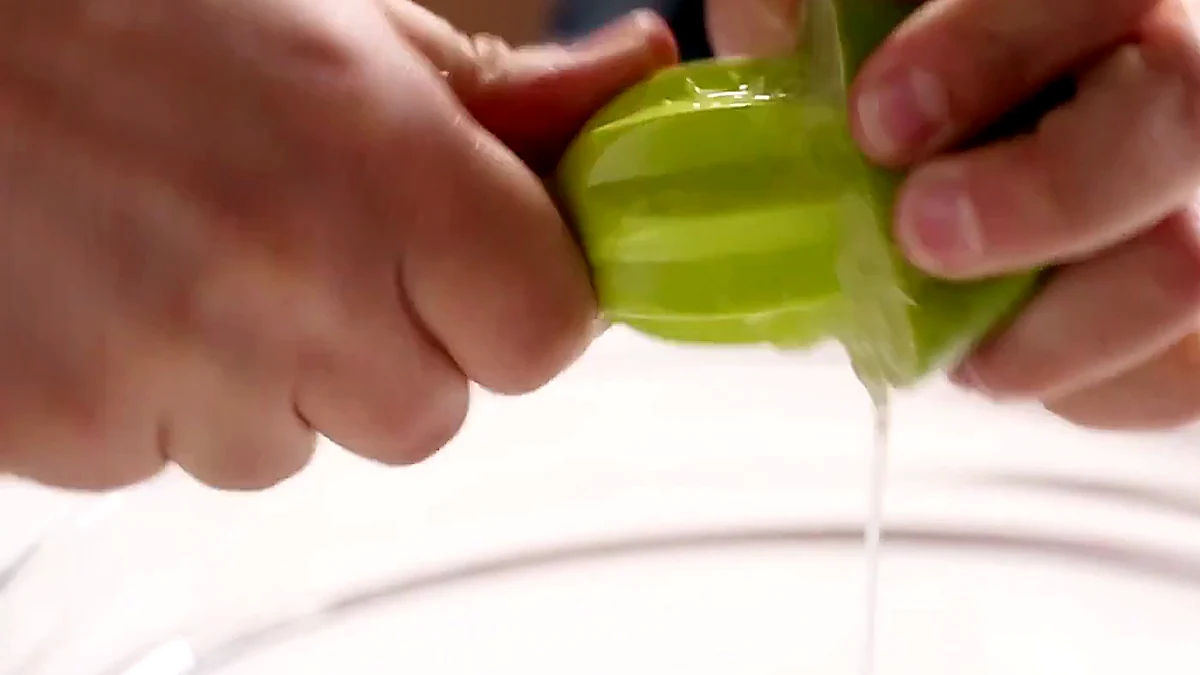 Lime juice being squeezed into a bowl