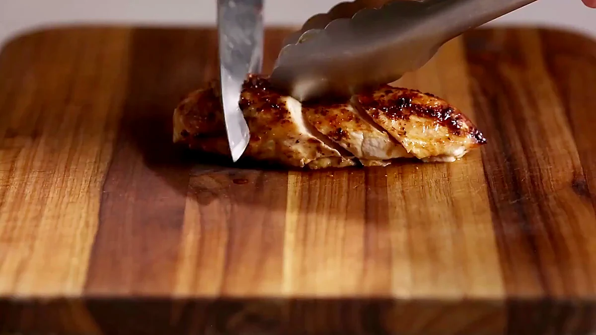 Cooked lime chicken being sliced on a cutting board