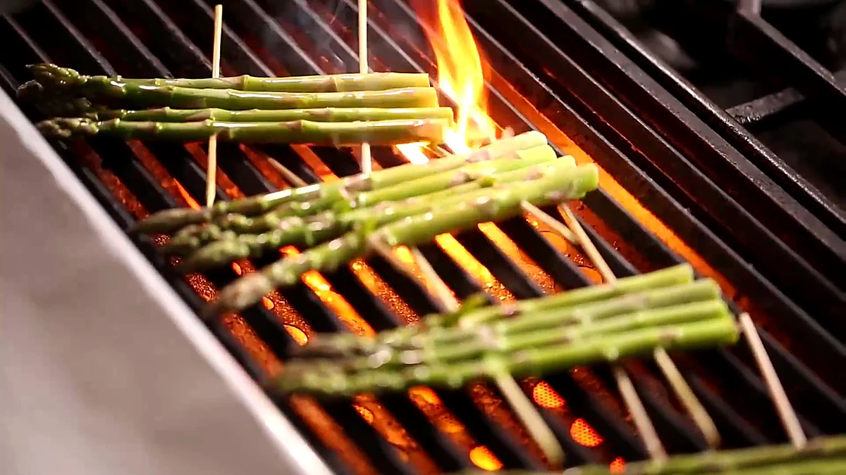 Asparagus skewers grilling over flame
