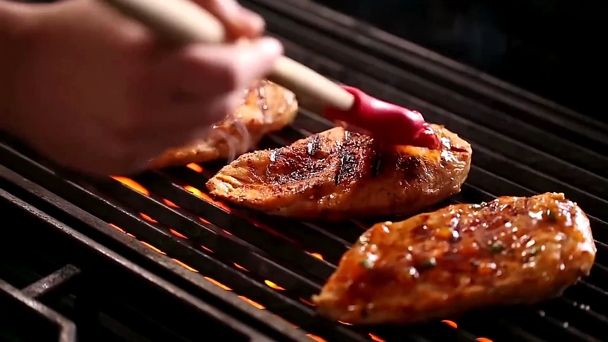 Peach glaze brushed over chicken on the grill