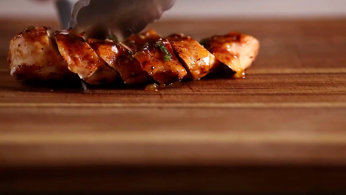 Sliced peach glazed chicken on a cutting board