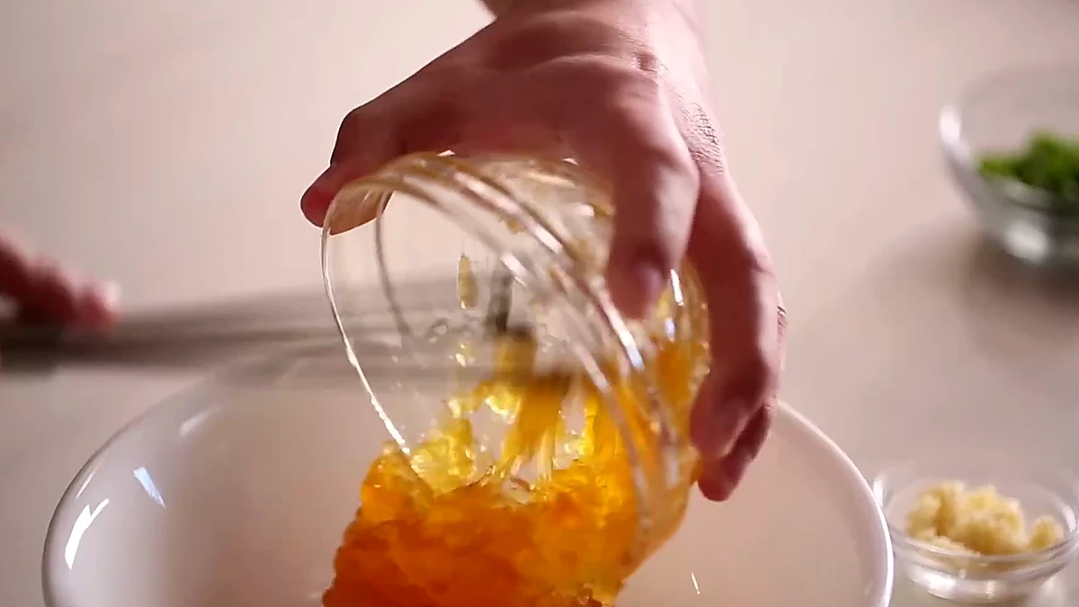 Peach preserves being added to a bowl for chicken glaze