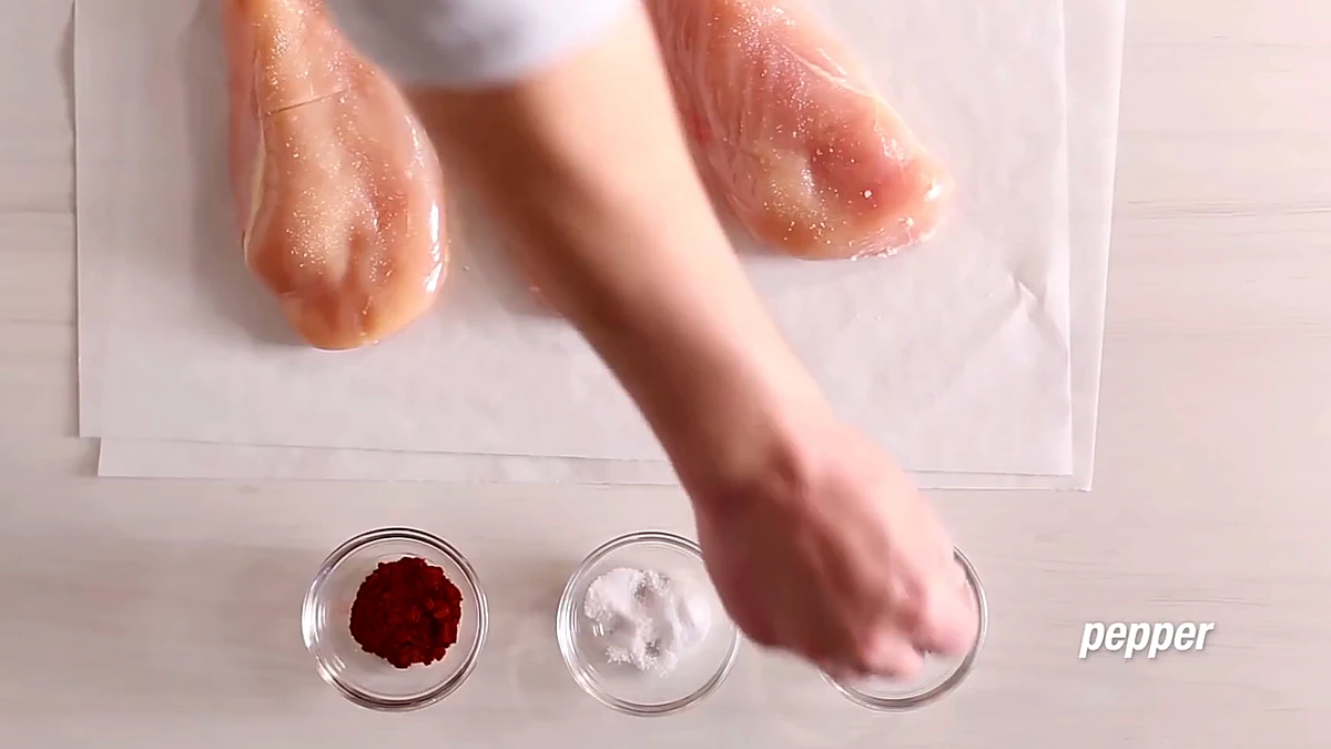 Pepper being added to chicken breasts