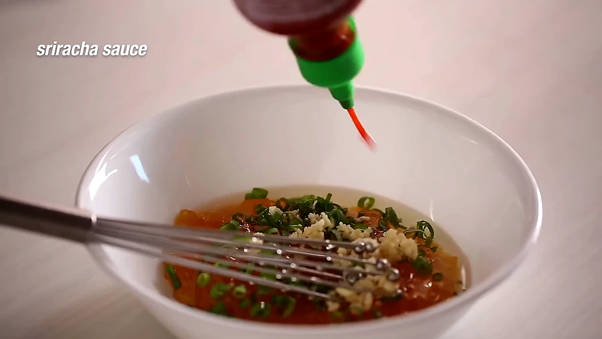 Sriracha being added to peach chicken glaze