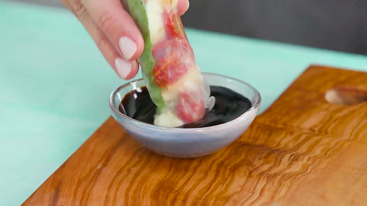 Roasted tomato Caprese summer roll dipped into balsamic