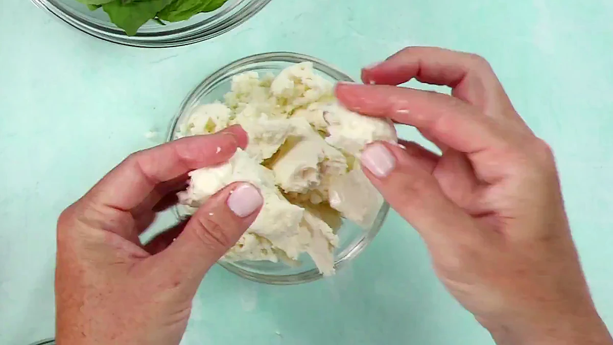 Mozzarella cheese being torn into small pieces