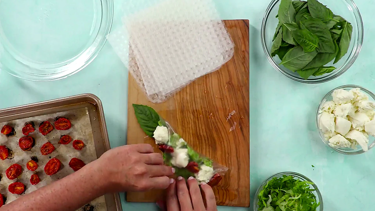 Finished Caprese summer roll being held after rolling