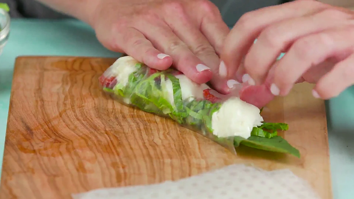 Sides tucked while rolling a Caprese summer roll