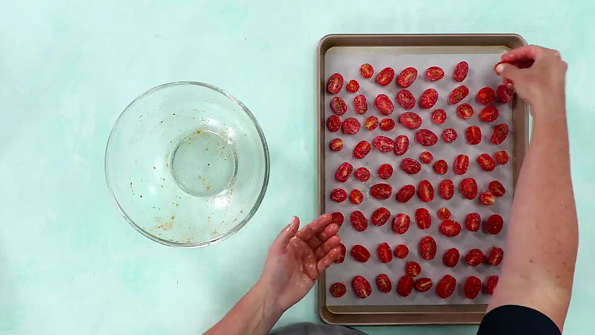 Seasoned grape tomatoes spread on a sheet pan