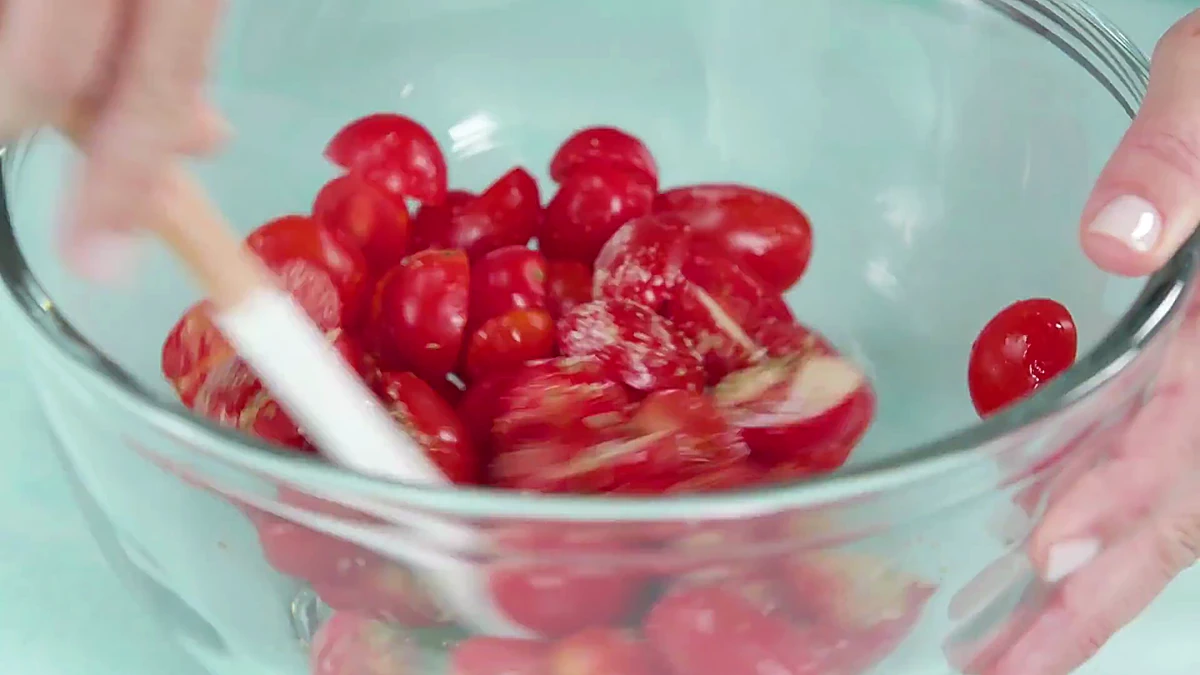 Seasoned grape tomatoes stirred in a bowl