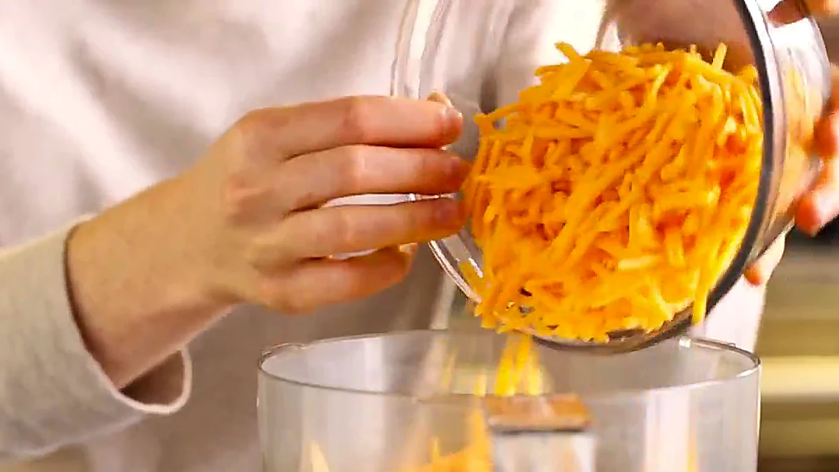 Shredded cheddar added to tortilla chips