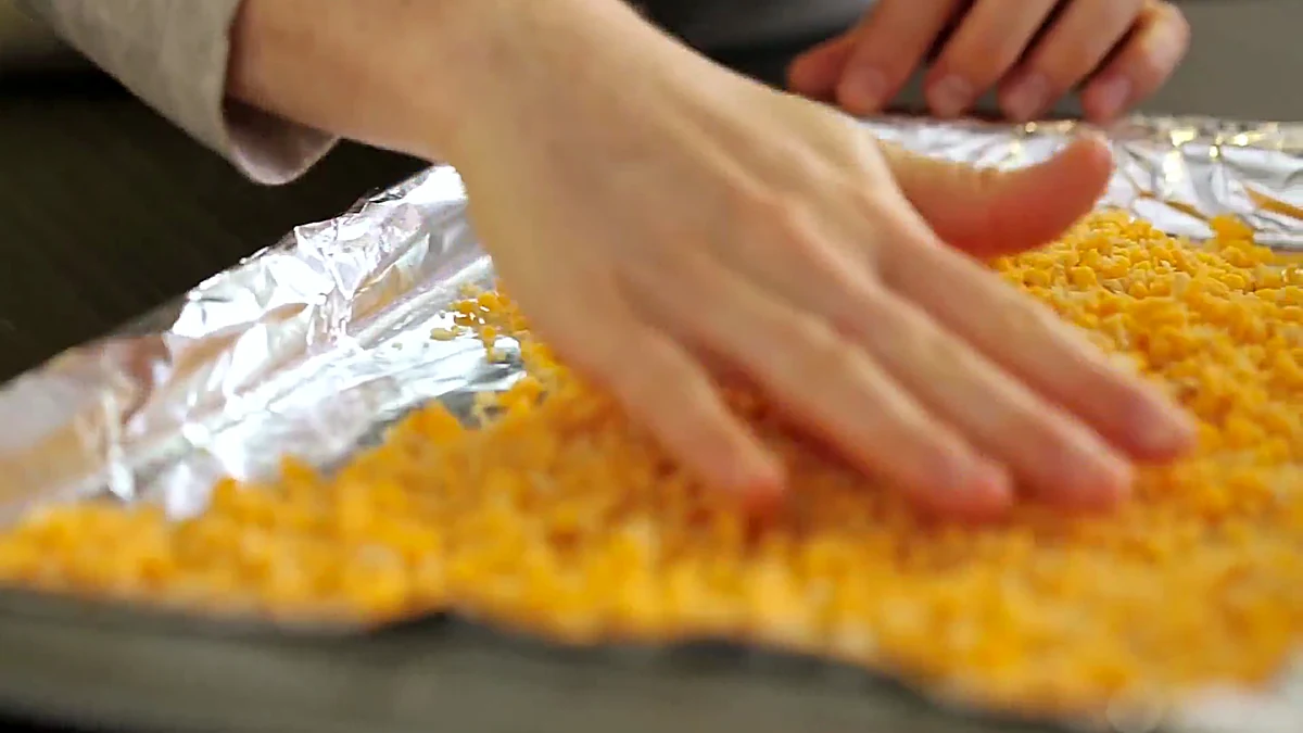 Cheesy tortilla crumble spread on a baking sheet