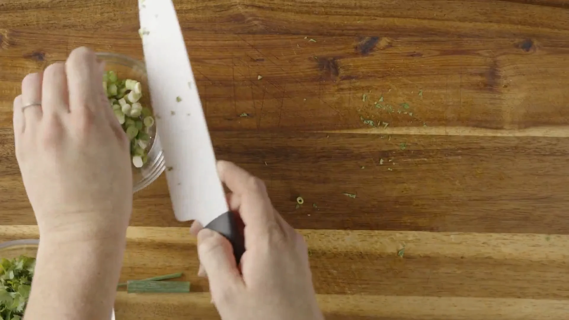 Green onions being sliced into thin rings on a cutting board