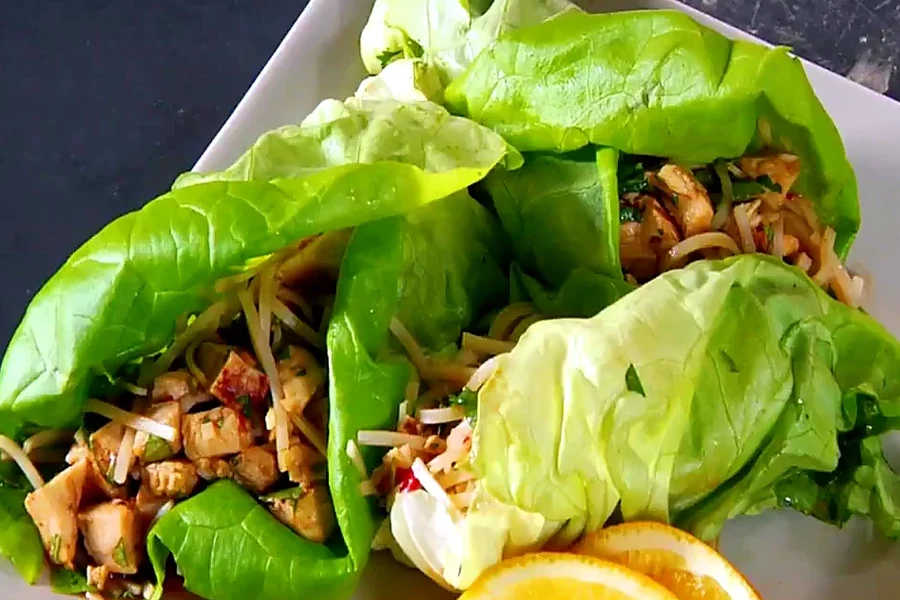 Finished spicy Asian lettuce wraps with orange wedges