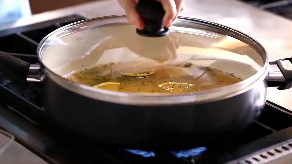 Citrus poaching liquid covered in a saute pan