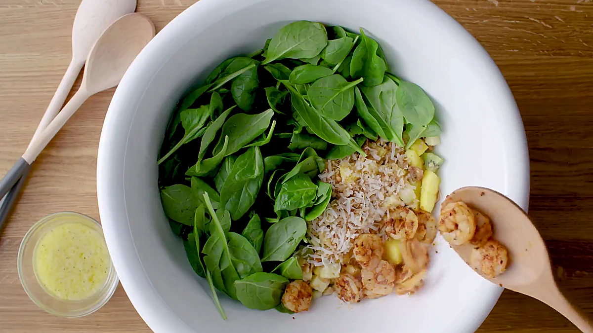 Greens fruit coconut and shrimp in a salad bowl
