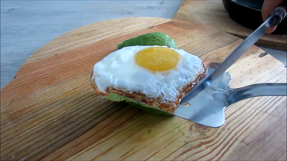 Fried egg placed on avocado burger filling