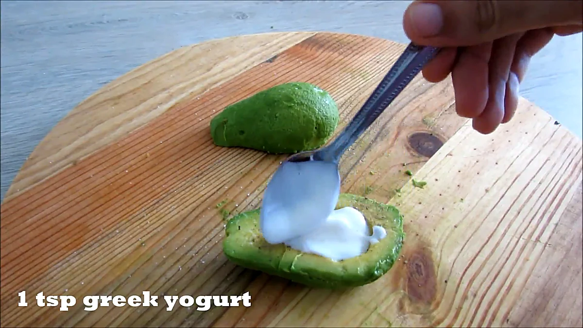 Greek yogurt spooned into avocado half