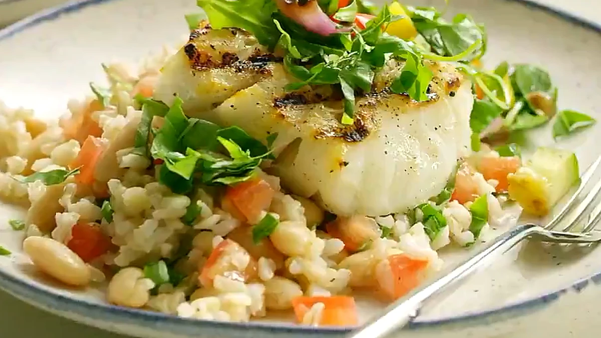 Close view of grilled basil pepper fish over white bean rice
