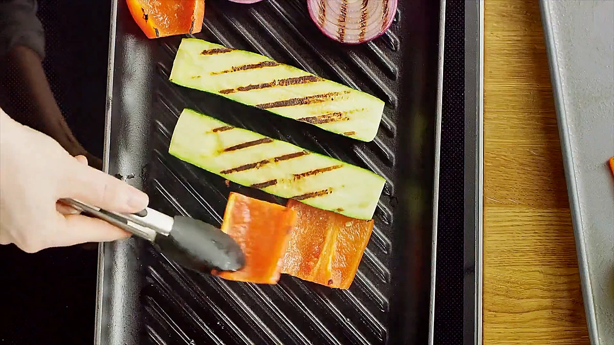Zucchini, peppers, and onion grilling with char marks