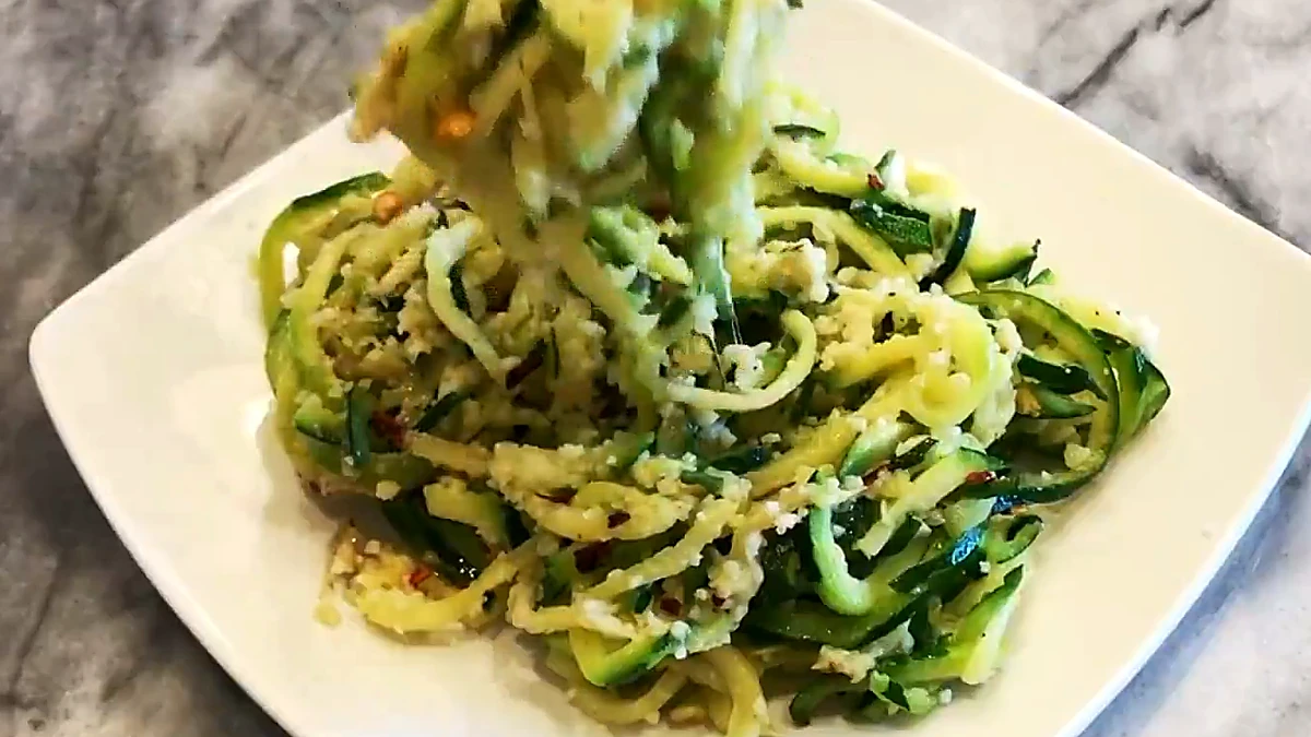 Fork lifting cheesy garlicky zucchini noodles