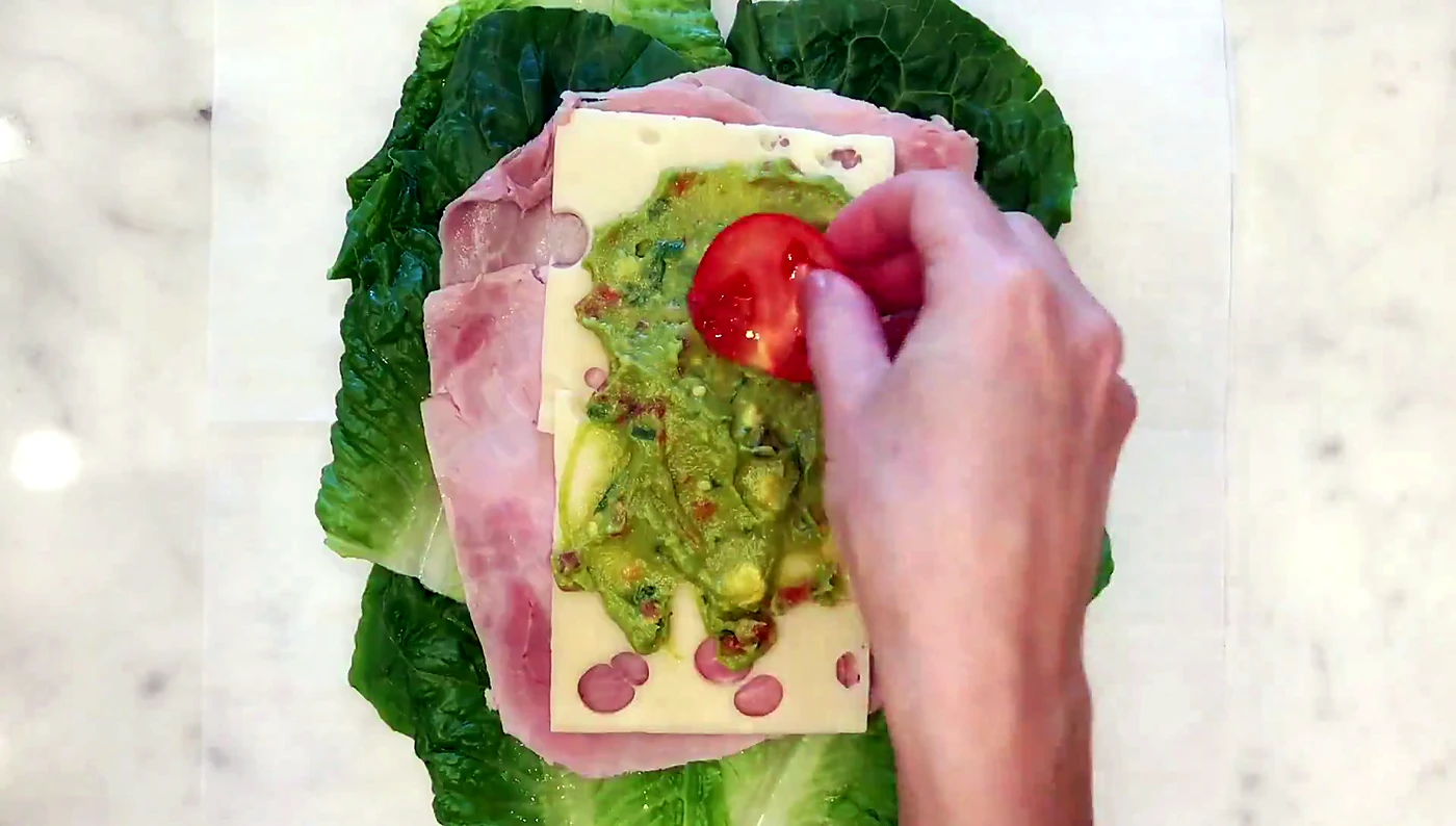 Tomato slices added to a lettuce wrap sandwich