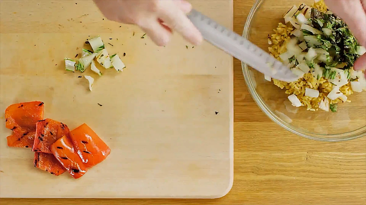 Grilled bok choy and red pepper chopped on a cutting board