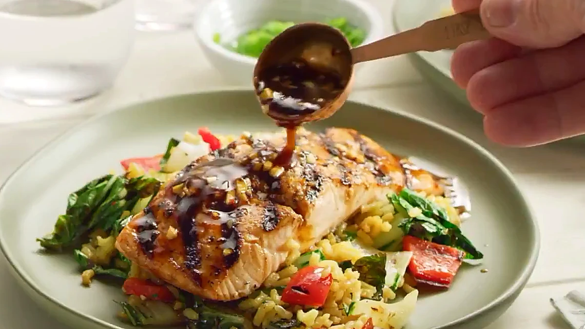 Grilled salmon set over the rice salad with marinade drizzled on top