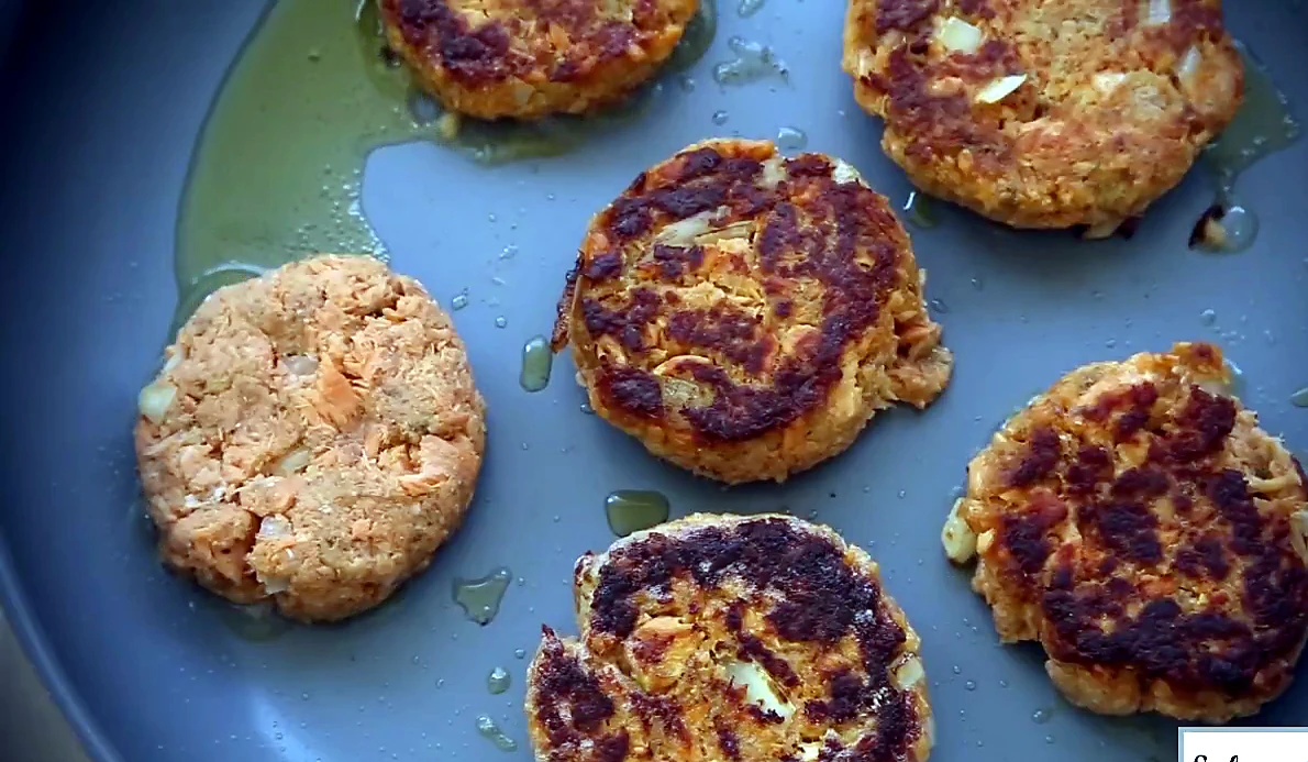 Close view of browned salmon patties in the pan
