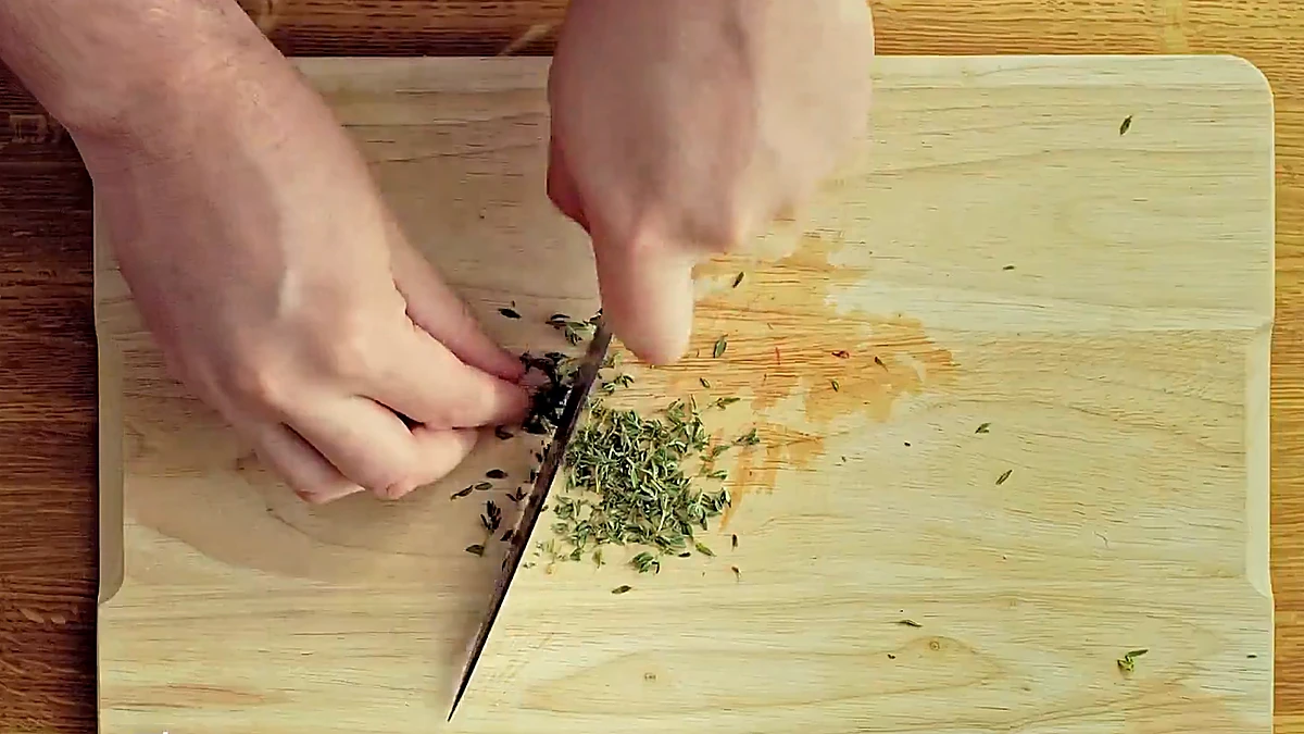 Fresh thyme being chopped on a wooden board