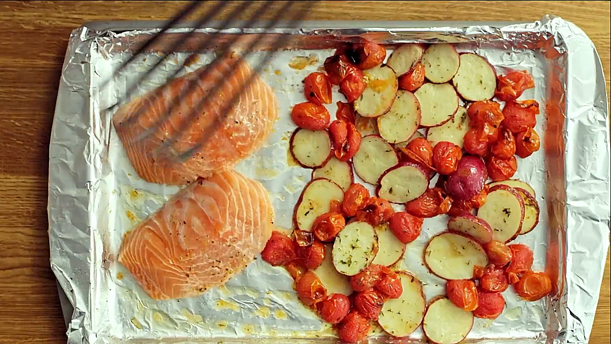 Salmon fillets added to the sheet pan with the roasted vegetables